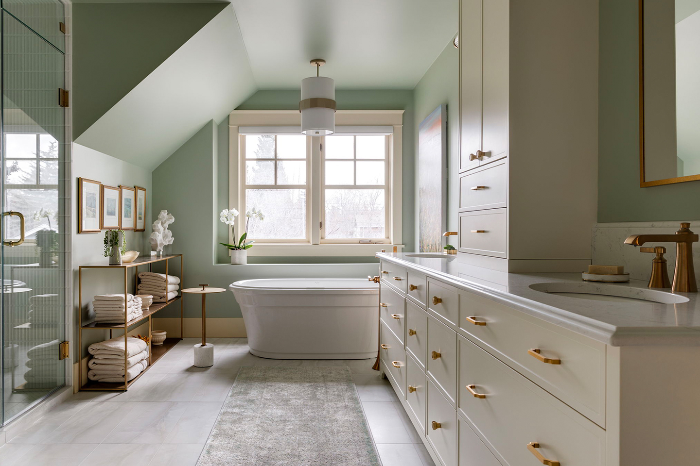 A newly renovated bathroom with light green walls, cream cabinetry, a large soaker tub and copper fixtures.