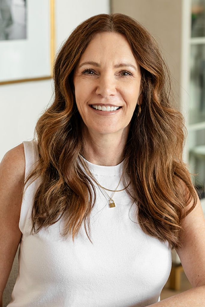 A professional headshot of a woman sitting in an interior design office.