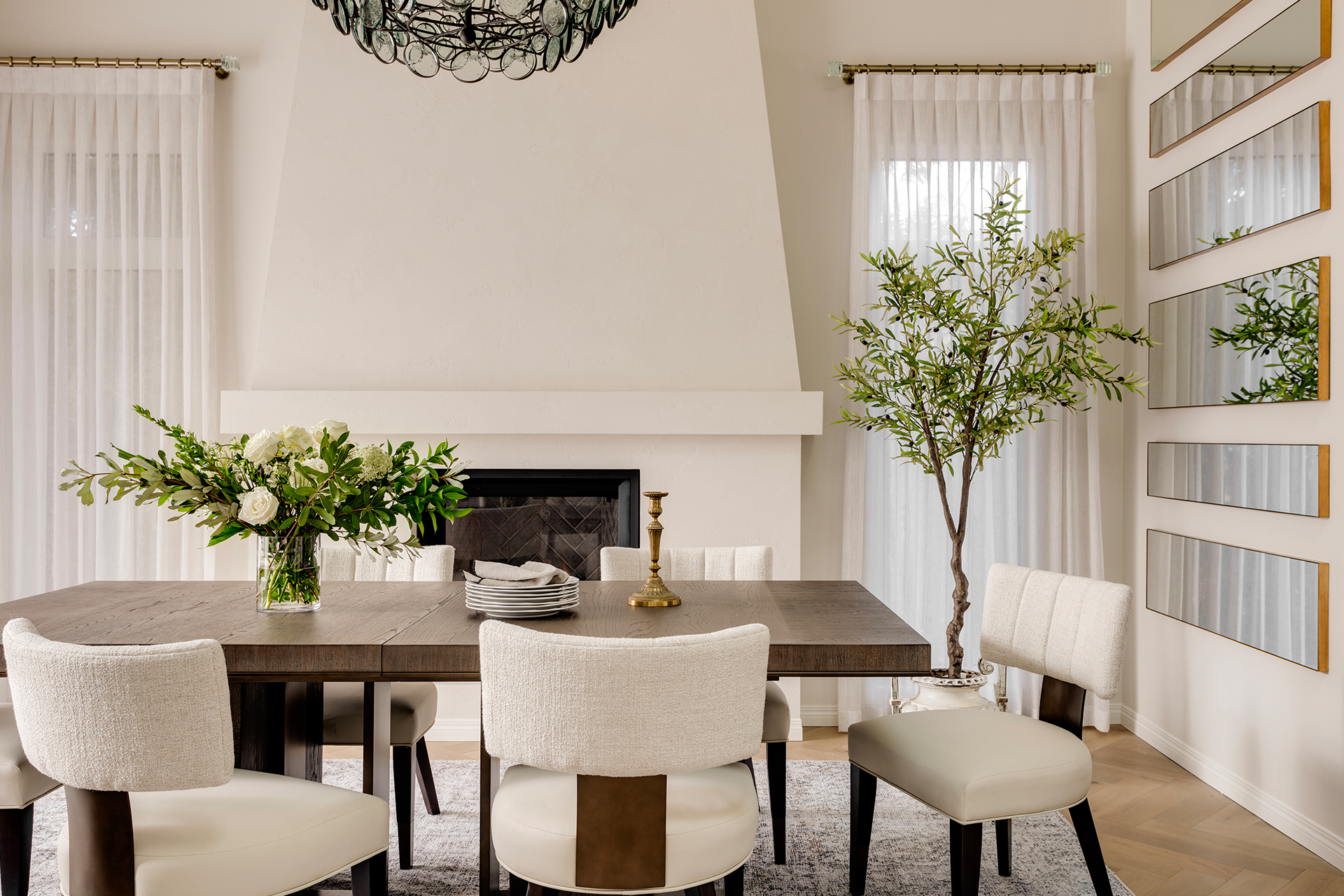 A beautiful off white dining room with a tall ceiling and large custom fireplace.