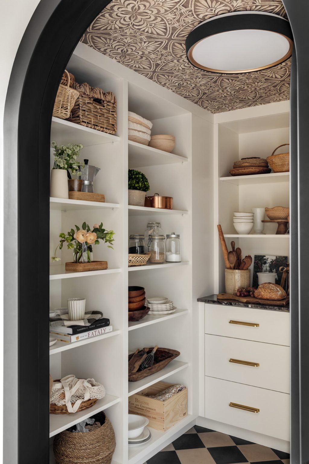 A black arched designer door opening into a new kitchen pantry.