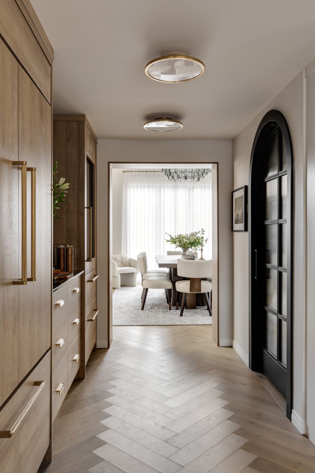 A beautiful hallway with custom built-ins looking into a bright modern dining room.